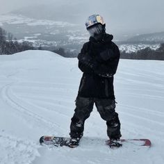 a snowboarder is standing in the snow with his board