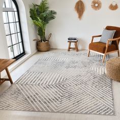 a living room with white walls and wooden chairs, rugs and potted plants