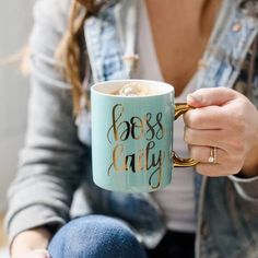 a woman is holding a coffee mug with the words boss early on it in gold lettering