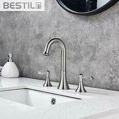 a bathroom sink with two faucets and soap dispenser next to it