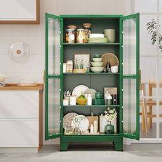 a green cabinet filled with dishes in a kitchen next to a table and chairs on the floor