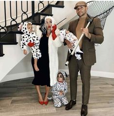 a man and two women dressed up as dalmatian dogs, one holding a baby