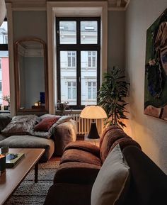 a living room filled with furniture and a large window next to a wall mounted painting