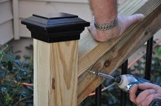 a man is using a drill to attach a post on a fence rail with a naildriver