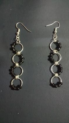 two pairs of black beads are hanging from silver earwires on a leather surface