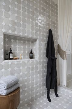 a white tiled bathroom with shelves on the wall