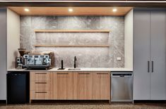 a modern kitchen with stainless steel appliances and wood cabinetry, along with marble walls