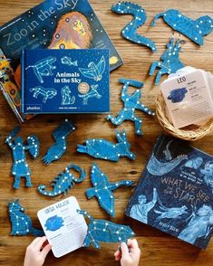 children's hands are playing with blue paper cutout animals and books on a wooden table