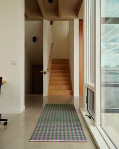 a room with a chair, desk and rug on the floor