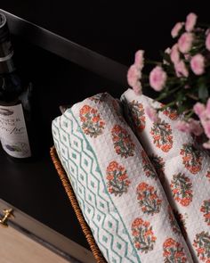 a bottle of wine sitting next to a basket with some flowers on top of it