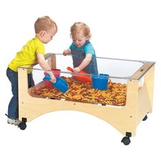 two young children playing with toys in a play table