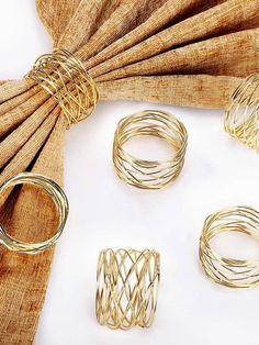 four pieces of gold wire sitting on top of a table next to a brown curtain