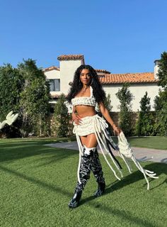 a woman dressed in white and black is posing on the grass with her arms around her waist