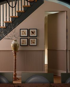 a staircase with pictures on the wall next to it and a vase filled with flowers