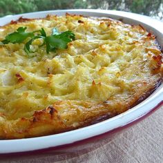 a casserole dish with cheese and herbs in it sitting on a table outside