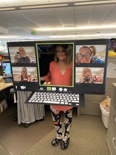 a woman standing in an office holding up a laptop computer with multiple pictures on the screen