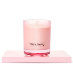 a pink candle sitting on top of a wooden block in front of a white background