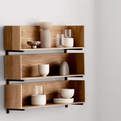 three wooden shelves with bowls and cups on them