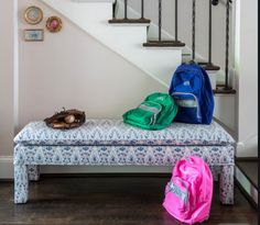 two backpacks are sitting on a bench in front of the stairs, and one bag is next to it