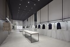 an empty clothing store with clothes hanging on the wall and tables in front of them