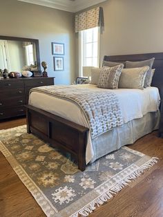 a large bed sitting on top of a wooden floor next to a dresser and mirror