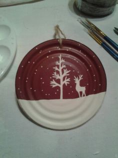 a red and white plate with a deer on it next to some paintbrushes