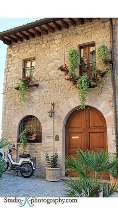 a scooter parked in front of a building with flowers on the windows and doors