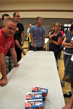 a group of people standing around a table with food on it and boxes of donuts