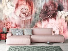 a pink couch sitting in front of a wall mural with flowers on it's side