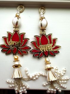 two red and white earrings with pearls hanging from them