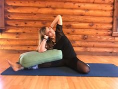 a woman sitting on a yoga mat talking on the phone and holding her leg up