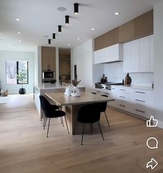 an open kitchen and dining area with white cabinets, black chairs, and wood flooring