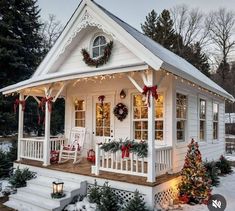 a small white house with christmas decorations on the porch