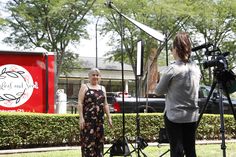 a woman is standing in front of a camera set up for a photo shoot outside