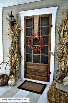 a front door decorated for fall with pumpkins and corn