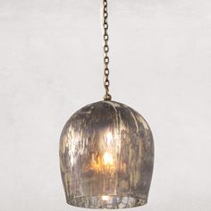 a metal light hanging from a chain on a white wall with no one in it