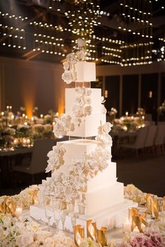 a tall white wedding cake sitting on top of a table covered in flowers and candles