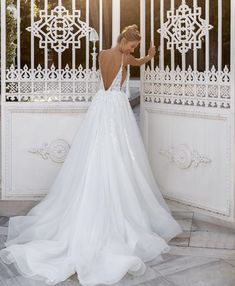 a woman in a white wedding dress is standing by an iron gate with her back to the camera