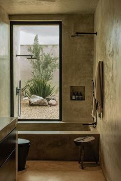 a bathroom with a large window that looks out onto the desert and rocks in the bathtub