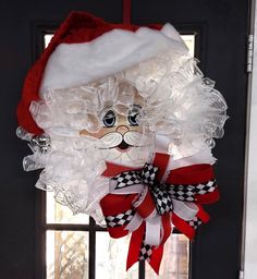 a door hanger with a santa claus hat on it's head and checkered ribbon