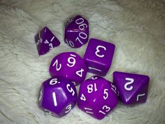 purple dice with white numbers on them laying on a fur covered floor, next to each other