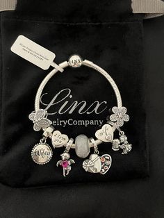 a bracelet with charms on it sitting in a black bag next to a name tag