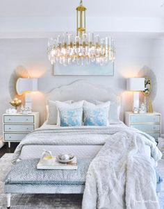 a bedroom with a large bed, chandelier and two tables in front of it