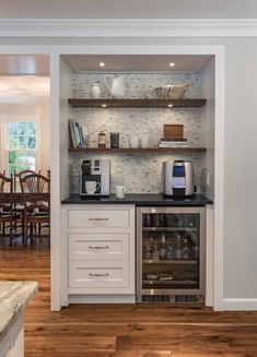 a kitchen with white cabinets and black counter tops, an oven and coffee maker in the corner