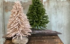 two small pine trees sitting on top of a wooden table next to rocks and wood planks