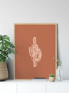 a cactus print on a wall next to a potted plant