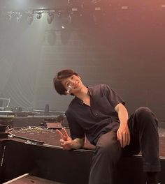 a man sitting on top of a stage talking on a cell phone while holding his hand up