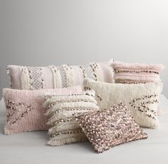 a bunch of pillows sitting on top of a white table next to each other with sequins