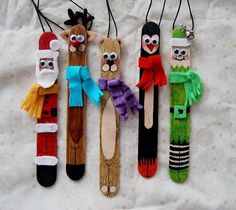 four wooden peg puppets with santa claus, snowman and elves on them hanging from strings