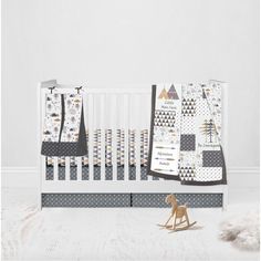 a baby crib bedding set includes grey and white sheets, black and gold geometric comforters, and a wooden rocking horse